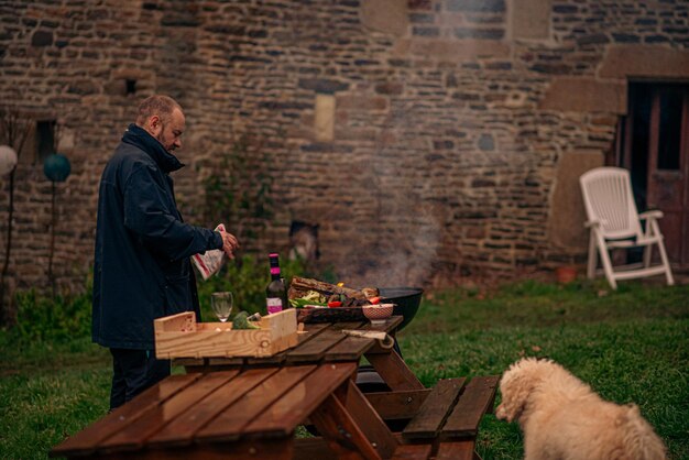 Un hombre en el patio hace una parrilla.