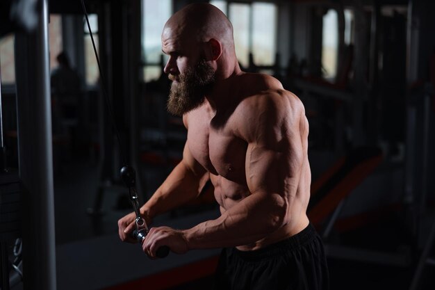 Un hombre de pecho desnudo y barba está haciendo ejercicio en un gimnasio.