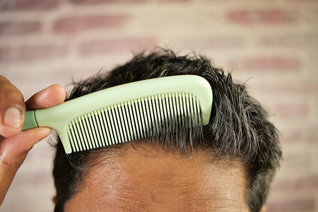 Hombre peinando el cabello con peine de cerca