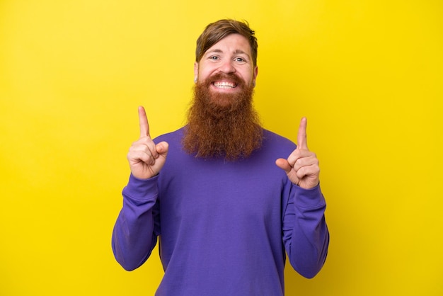 Hombre pelirrojo con barba aislado de fondo amarillo señalando una gran idea