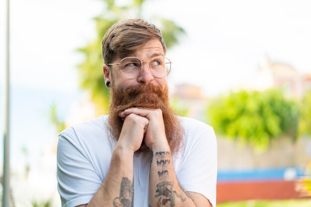 Hombre pelirrojo con barba con gafas y cansado