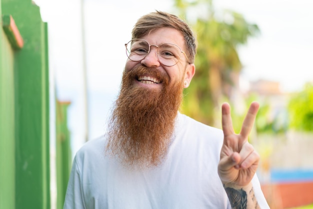 Hombre pelirrojo con barba con gafas y haciendo el signo de OK