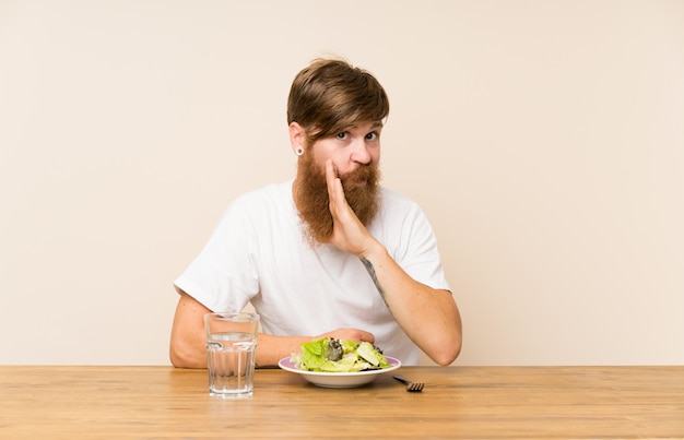 Hombre pelirrojo con barba larga y ensalada susurrando algo