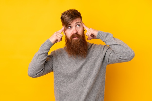 Hombre pelirrojo con barba larga sobre pared amarilla aislada que tiene dudas y pensamiento