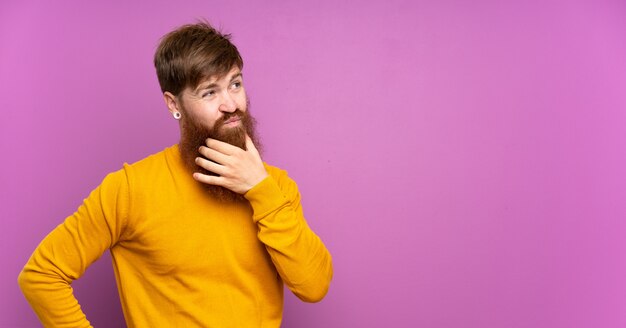 Hombre pelirrojo con barba larga sobre pensamiento púrpura aislado