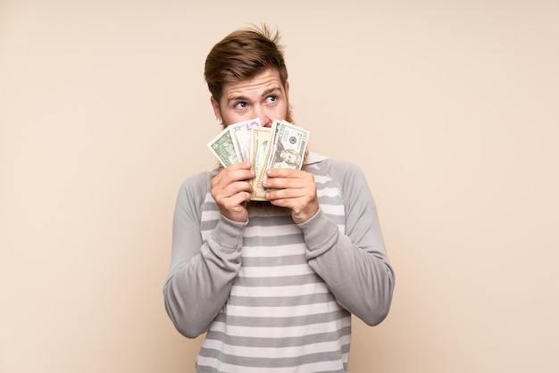 Foto hombre pelirrojo con barba larga tomando mucho dinero