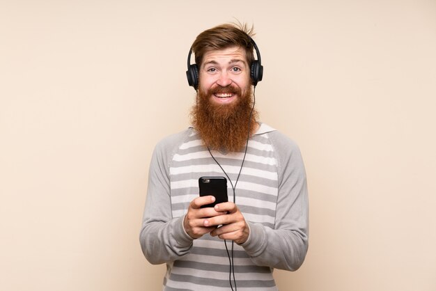 Hombre pelirrojo con barba larga usando el móvil con auriculares