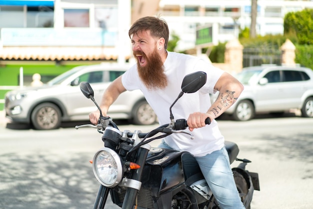 Hombre pelirrojo con barba con una motocicleta