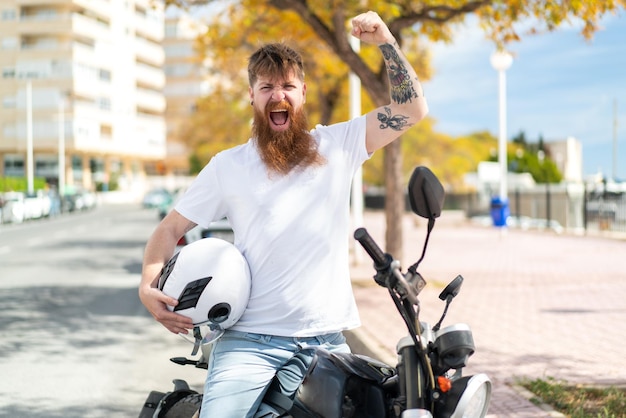 Hombre pelirrojo con barba con una motocicleta