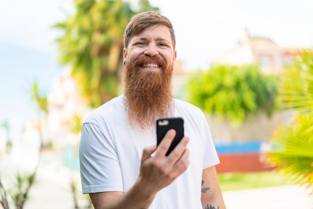 Hombre pelirrojo con barba a través de teléfono móvil