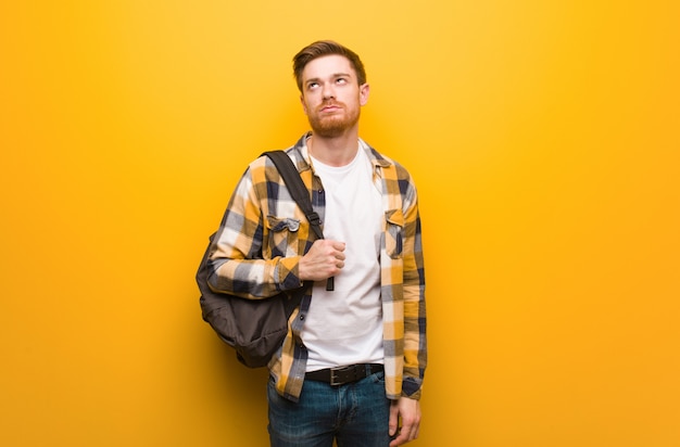 Hombre pelirrojo joven estudiante cansado y aburrido