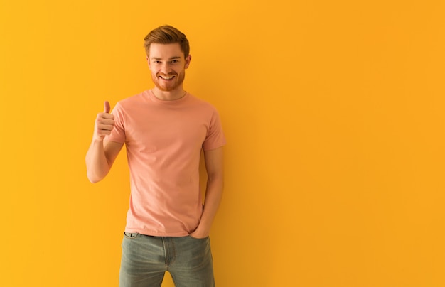 Hombre pelirrojo joven sonriendo y levantando el pulgar hacia arriba