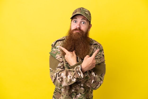 Hombre pelirrojo militar sobre aislado sobre fondo amarillo apuntando a los laterales que tienen dudas