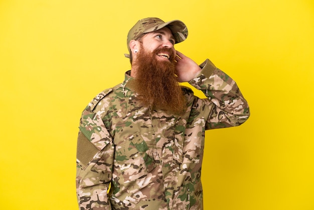 Hombre pelirrojo militar sobre aislado sobre fondo amarillo pensando en una idea