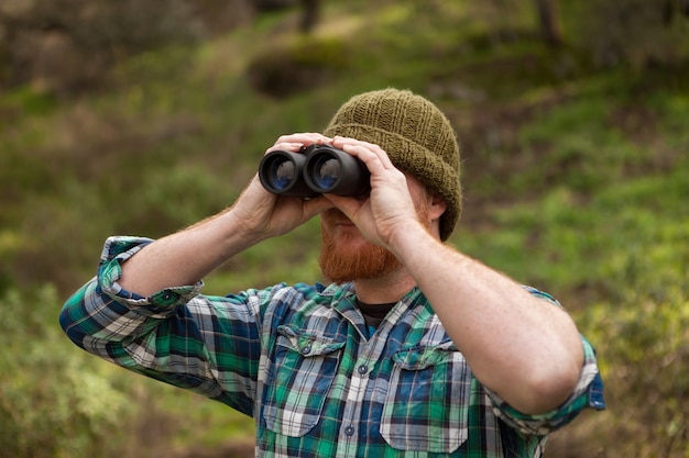 Hombre pelirrojo que mira lanzar un binocular