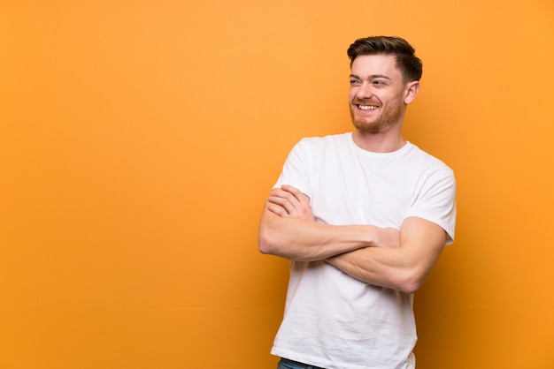 Hombre pelirrojo sobre pared marrón feliz y sonriente