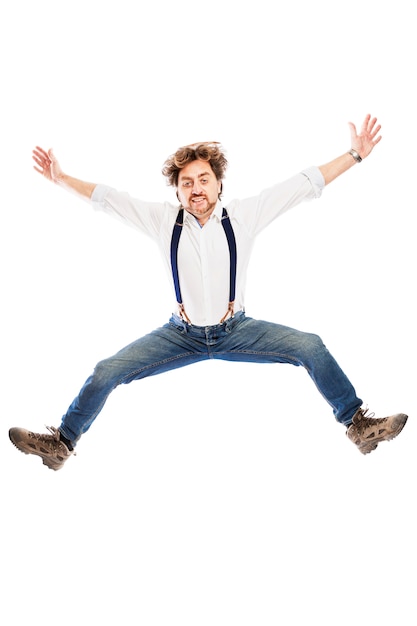 Un hombre pelirrojo sonriente con una barba en jeans y una camisa blanca está saltando. Aislado sobre la pared blanca. Vertical.