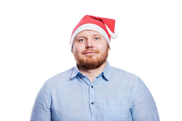 Hombre pelirrojo sonriente con sombrero de santa claus. Celebración de año nuevo y Navidad. Aislado.