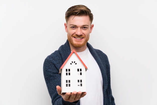 Foto hombre pelirrojo sosteniendo una casita