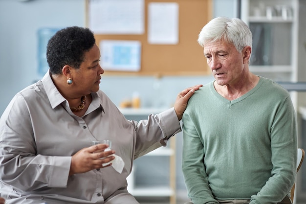 Hombre de pelo blanco deprimido compartiendo historias en un grupo de apoyo de salud mental