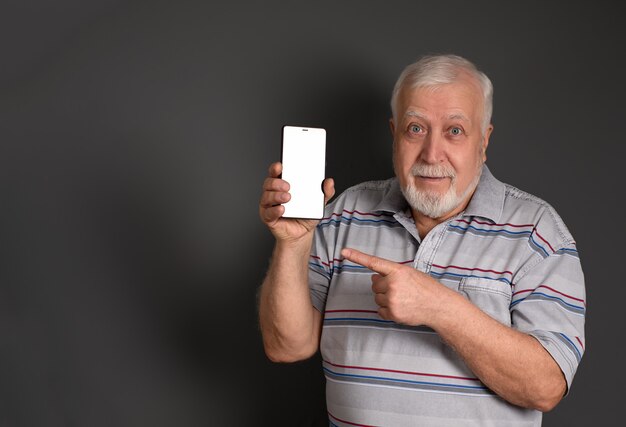 Hombre de pelo gris que sostiene un teléfono y apunta su dedo en gris