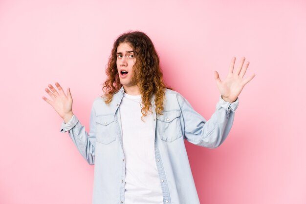 Hombre de pelo largo posando aislado está conmocionado debido a un peligro inminente