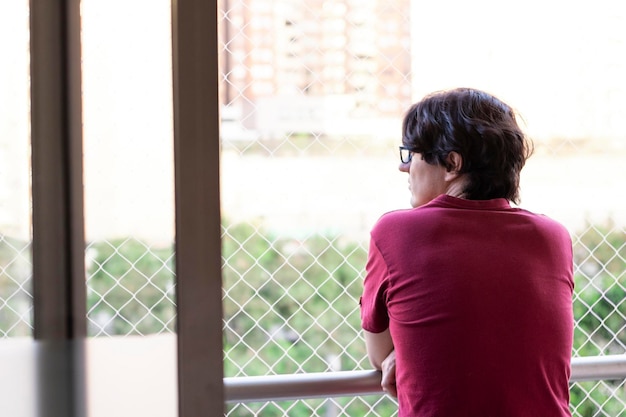 Hombre de pelo negro mirando por la ventana