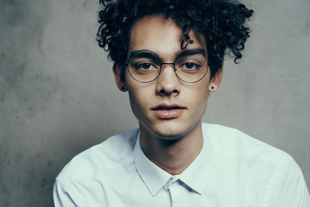 Hombre de pelo rizado con gafas y una camisa blanca sobre un fondo de tela modelo de sonrisa retrato en primer plano