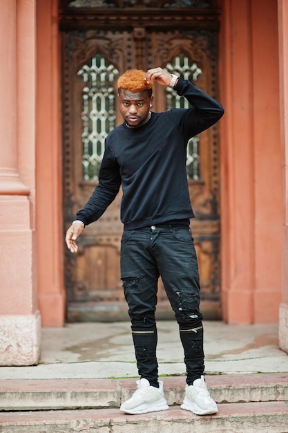 Hombre de pelo rojo africano usa traje negro posando al aire libre.