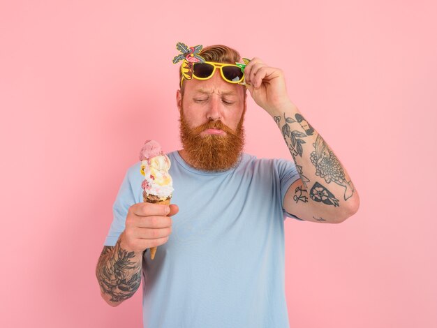 Hombre pensativo con barba y tatuajes come un gran helado