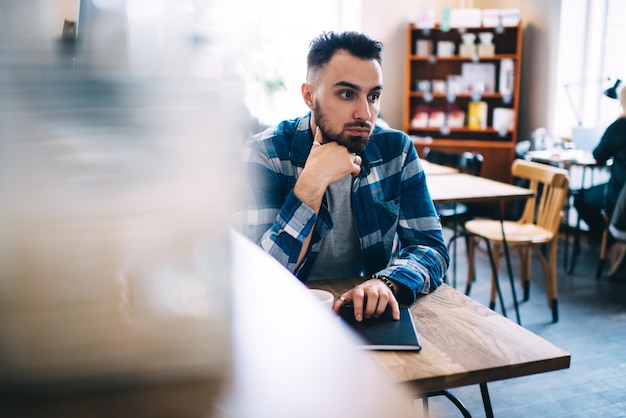 Hombre pensativo bebiendo café en la cafetería y mirando hacia otro lado