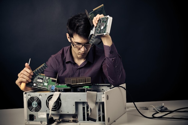 Hombre pensativo reparando el armario de la computadora en la mesa