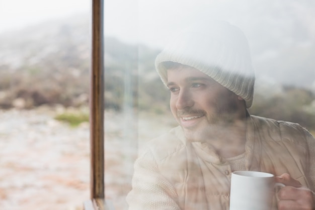 Hombre pensativo con taza mirando por la ventana