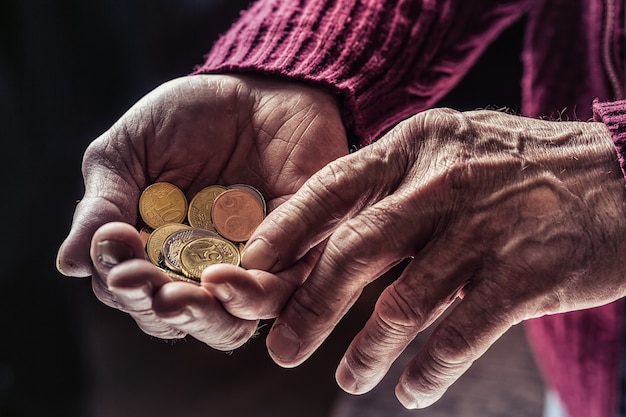 Hombre pensionista sosteniendo en las manos monedas de euro. Tema de pensiones bajas.