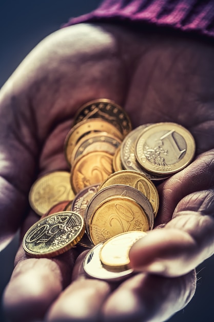 Hombre pensionista sosteniendo en las manos monedas de euro. Tema de pensiones bajas.