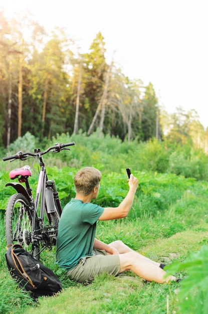 Foto un hombre se perdió en una bicicleta en un camino forestal de verano. falta de comunicación