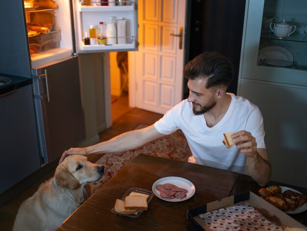 Foto hombre con perro en ángulo alto de cocina