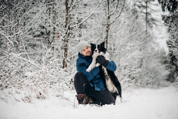 Hombre con un perro border collie blanco y negro en la nieve.
