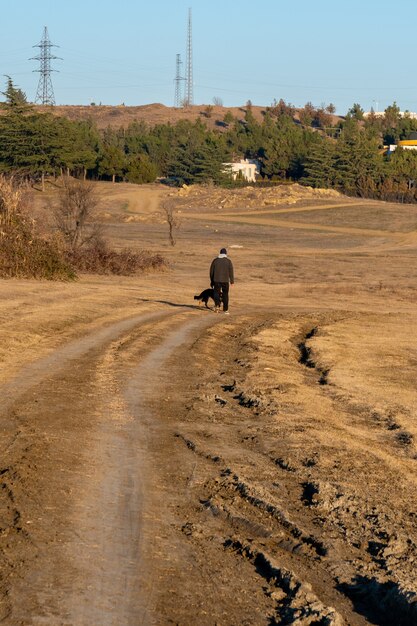 Foto hombre con perro en camino de tierra para coches