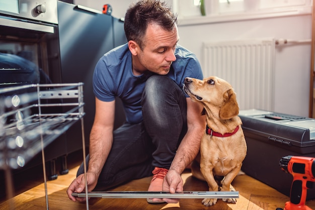 Hombre con perro construyendo armarios de cocina