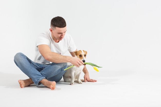 El hombre y el perro con flores se sientan en el suelo.