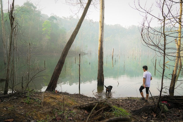 Hombre y perro pasan tiempo juntos en un lago brumoso