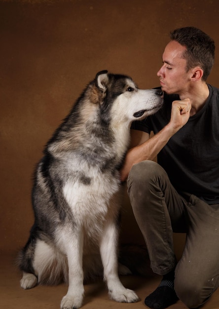 Foto hombre con perro sentado contra la pared