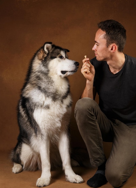 Foto hombre con perro sentado contra la pared