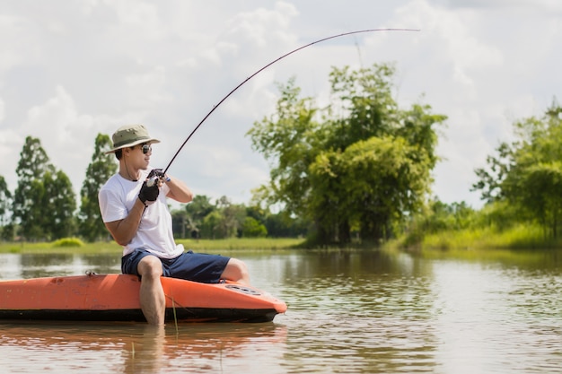 hombre de pesca a bordo en el río contra el fondo