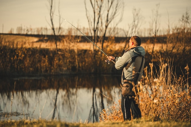 Un hombre pescador pescando en el río con una caña de pescar