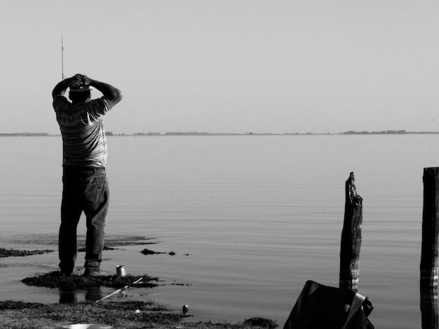 Hombre pescando en el mar contra un cielo despejado