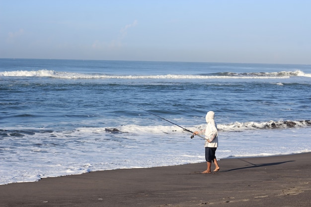 Hombre pescando en el mar desde la playa