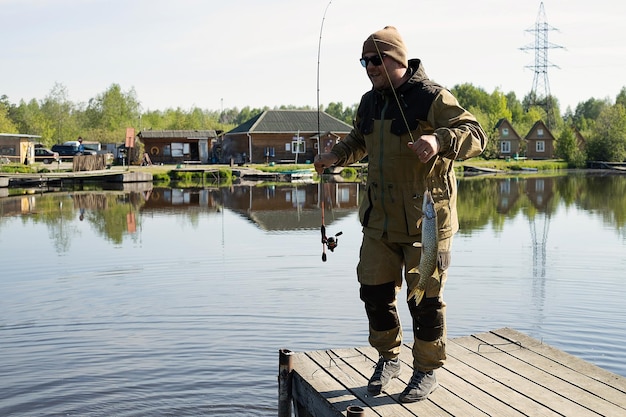 Hombre pescando en un muelle de madera cerca del lago