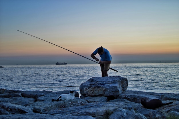 Hombre pescando en la orilla del mar contra el cielo